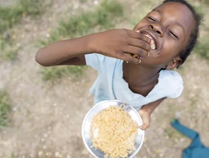 2020, Cite Soleil, displaced Haitian boy enjoying a warm meal, 2020