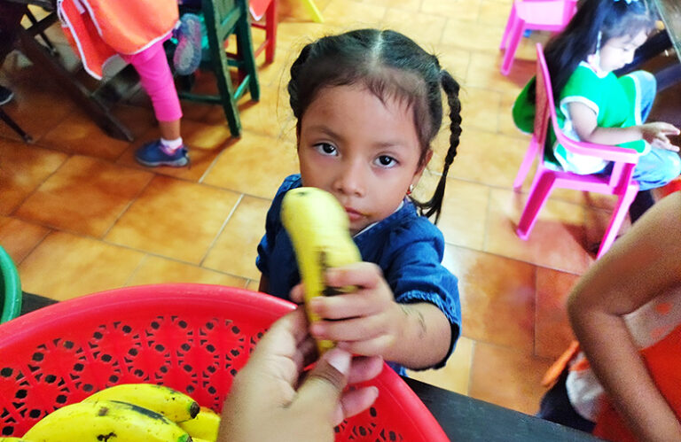 A young girl in Guatemala holds a banana as FFTP donors fight child malnutrition in Guatemala