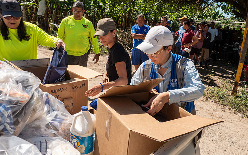 A group of people packing boxes with various items.