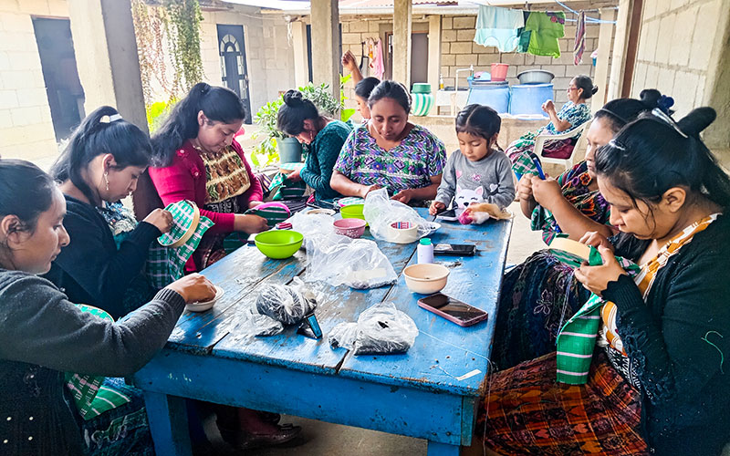 A group of women gathered around a table, engaged in sewing activities.