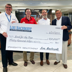 Food For The Poor President/CEO Ed Raine, Bill Bachrodt and Craig Bachrodt and their father, Lou Bachrodt stand in the FFTP lobby holding a big check representing a $30,000 gift to FFTP.