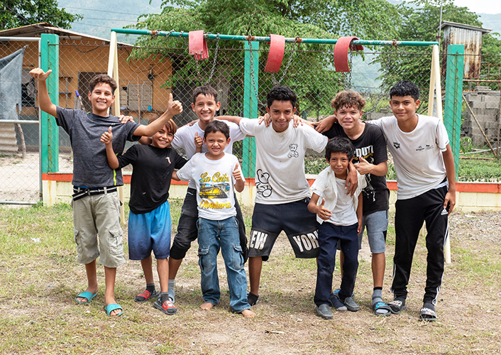 A group of boys smiling and posing together for a photograph outdoors. 