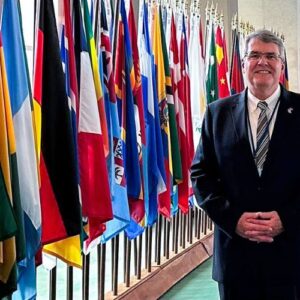 Ed Raine standing by flags at the united nations forum
