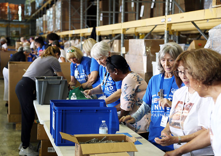 A diverse group of women wearing blue shirts, standing together exuding unity, captured in an engaging environment.