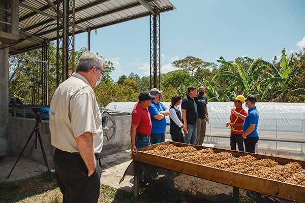 Food For The Poor President/CEO Ed Raine looks on as COMBRIFOL Cooperative members explaining the shelling and drying process of the coffee bean, a project funded by the charity’s donors.