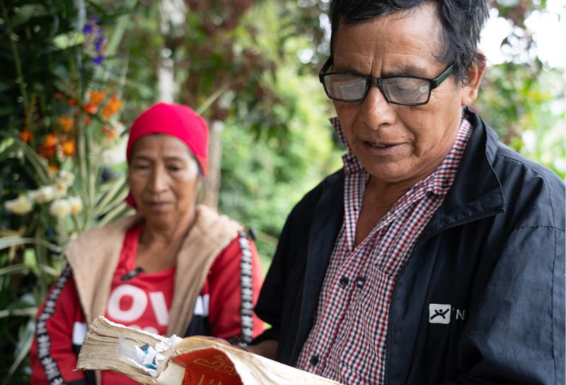 A Lenca man recites from a book while a Lenca woman looks on