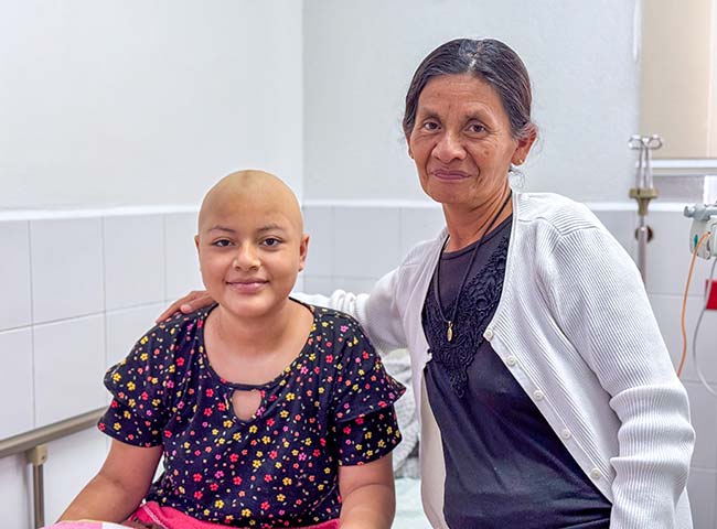 A woman and a child sit together in a hospital room.