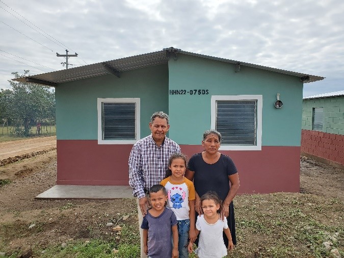 A family stands in front of their new home in Villanueva, Honduras