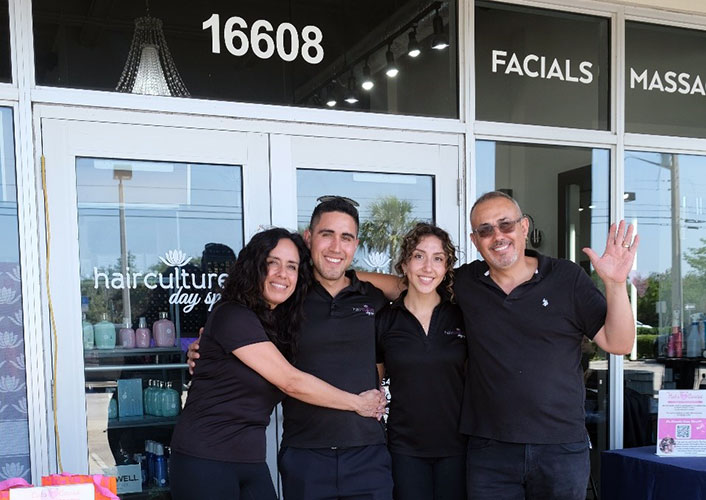 Four individuals standing outside a salon, with the salon's sign visible in the background.