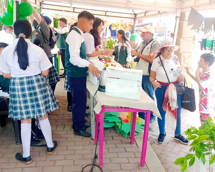 A group of people gathered around a table filled with food products made by young entrepreneurs in Colombia.