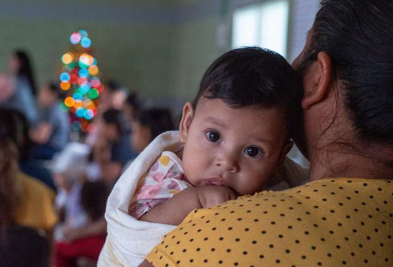 A baby girl rests her head on her mother's shoulder in a sustainable development community in Honduras