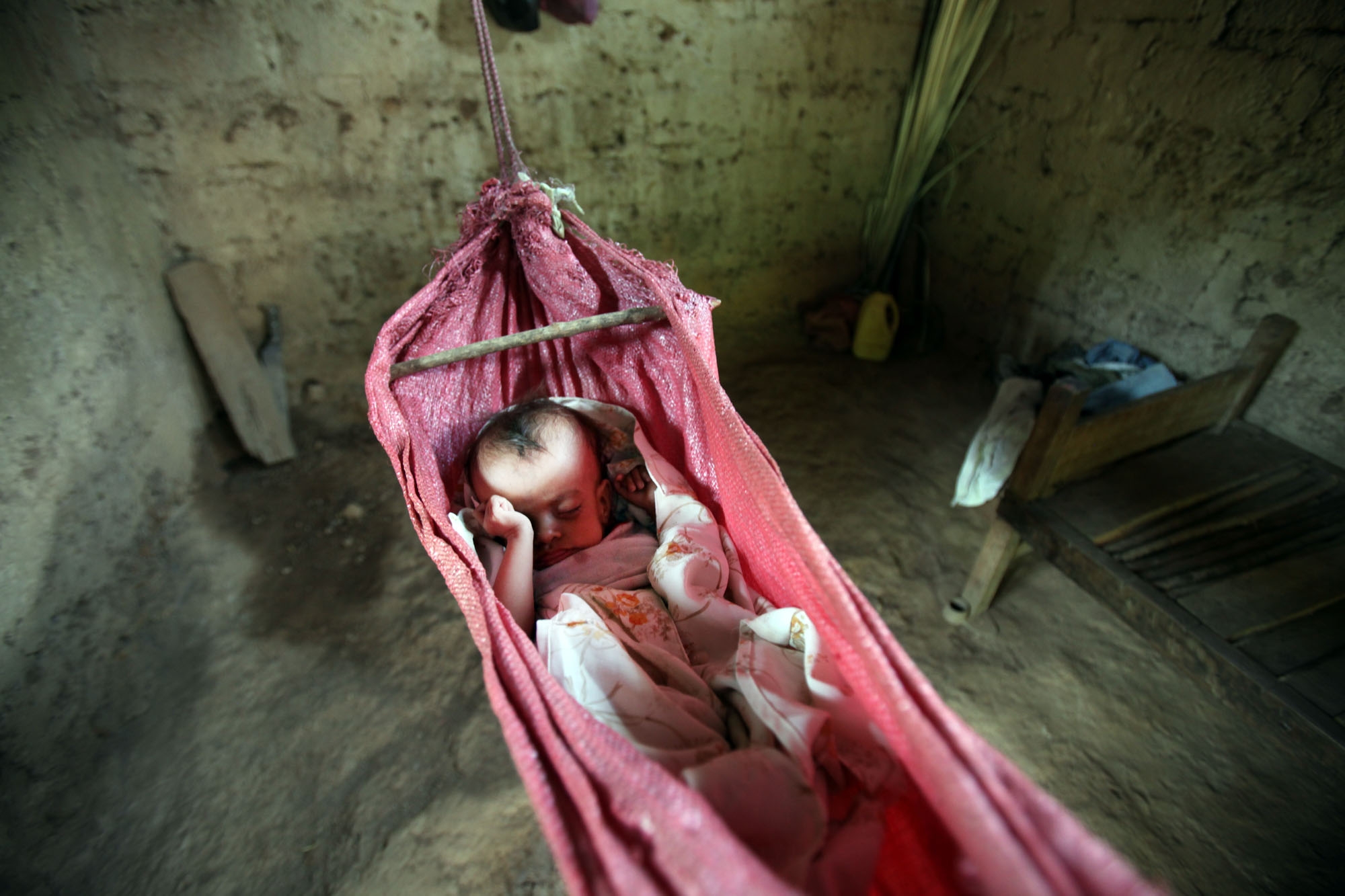 A baby sleeps in a precarious hammock