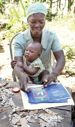 Marcelin held her baby in her lap as she carefully assembled Banana Bark cards.