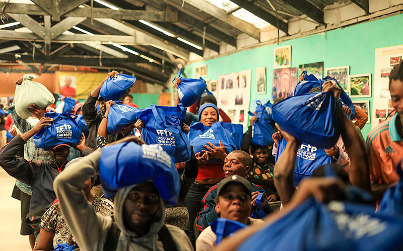 A group of people in a room holding blue bags.