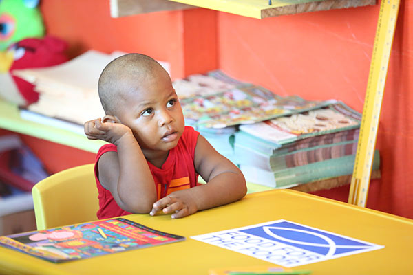 Young boy learning at a library in Guyana funded by food for the poor