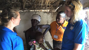 ((L to R) Gala committee members Kara Seeyle and Allison Venditti spoke to an expecting mom in her dirt-floor hut in Ganthier, Haiti.