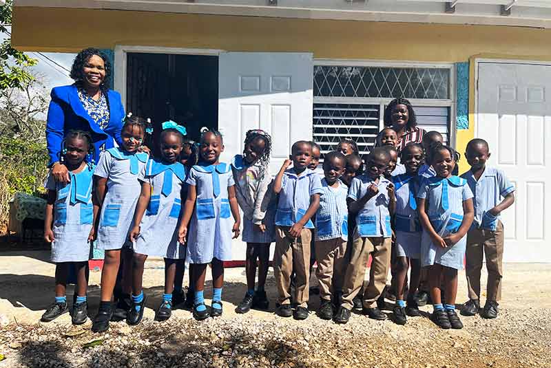 Students and teachers stand outside a school in Jamaica.
