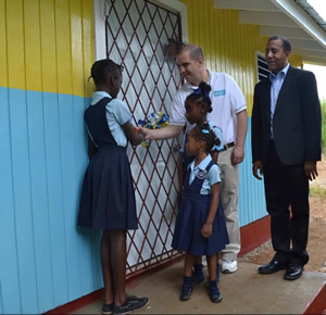 TEight 4 World Hope co-founder, Tom D'Amico, helps a student during the ribbon cutting ceremony at St. Theresa All Age School in St. Andrew Parish.
