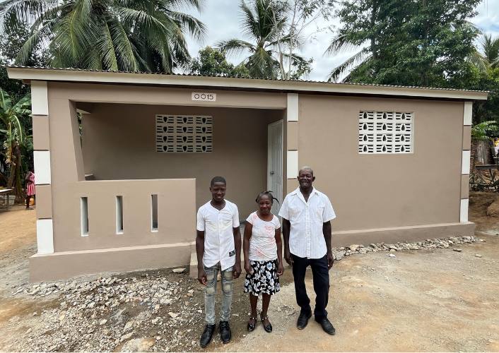A family stands in front of their new home in Patasson, Haiti. Families in Bondeau, Haiti will soon have their own homes like this
