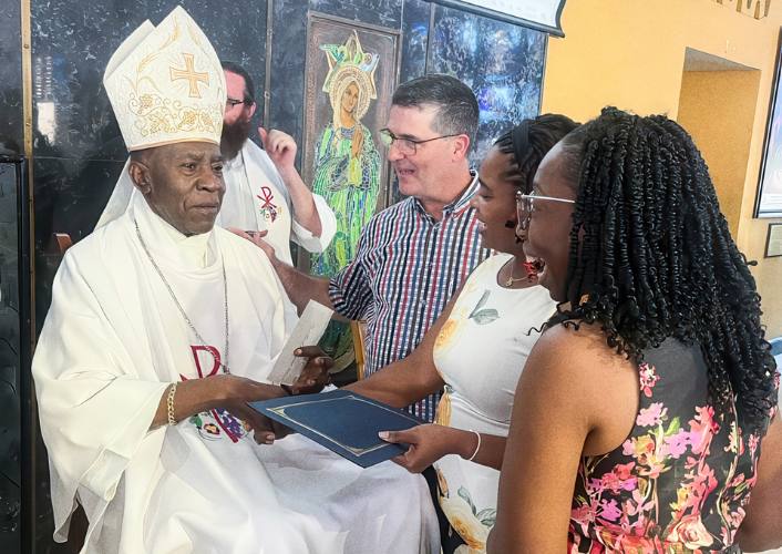 Bishop Burchell is greeted by 3 people who celebrate his retirement