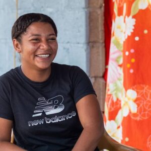 A woman in Honduras smiles in front of her FFTP home, fftp year-end 3x match will help more like her