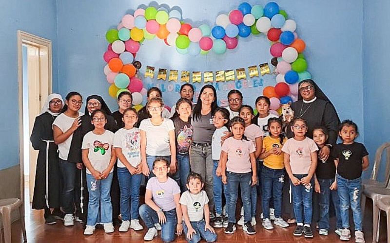 Mildred stands with children in the Angels of Hope program