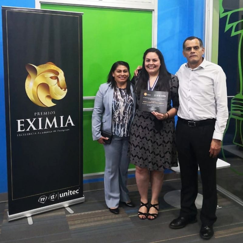 Monica standing with her parents at an award ceremony