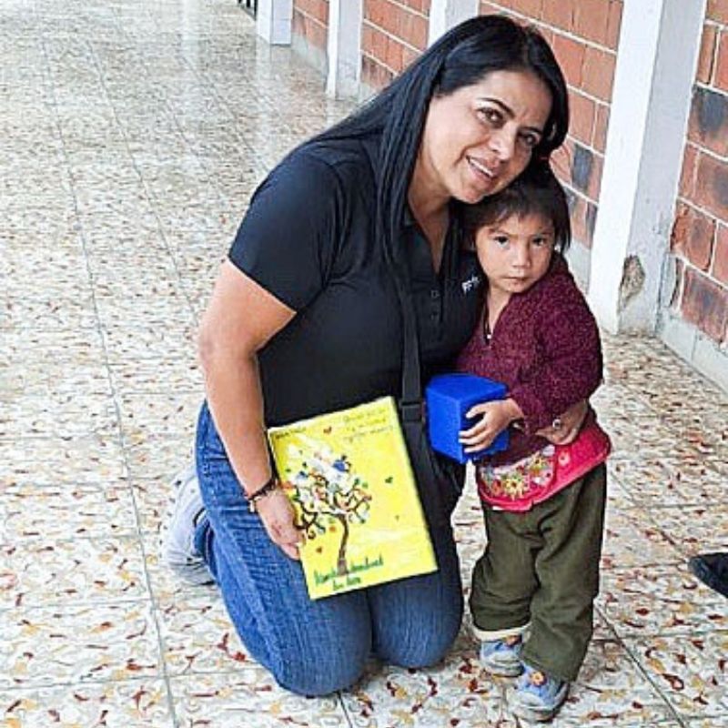 a woman kneels to hug a young child