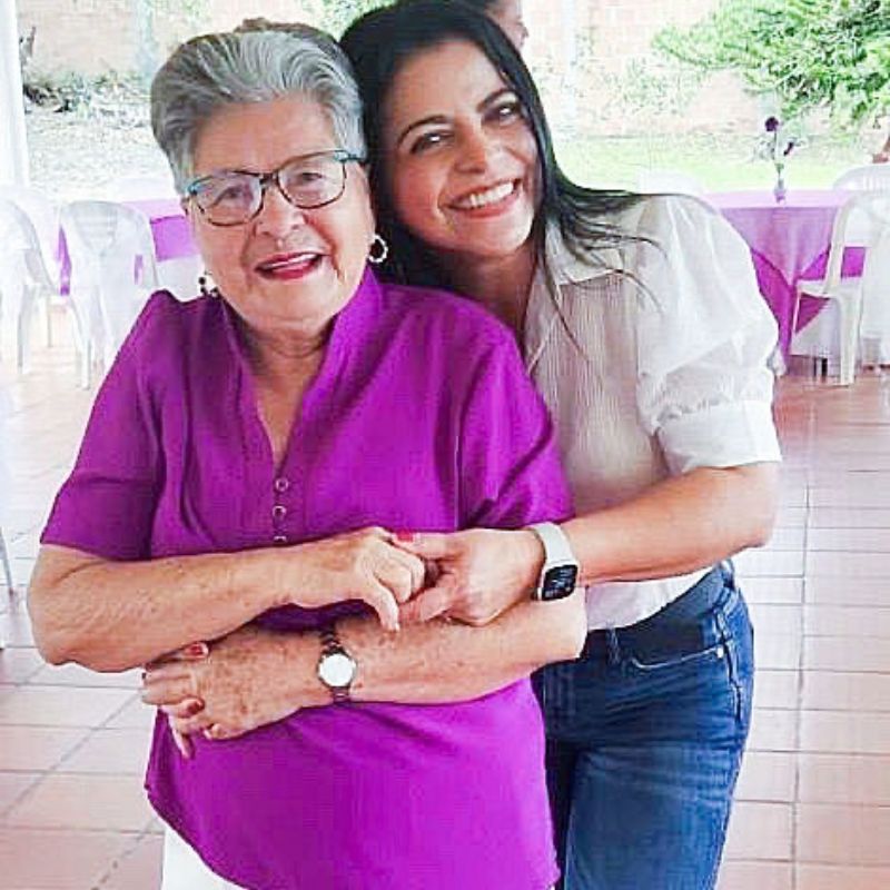 a daughter embracing her mother from behind, holding hands