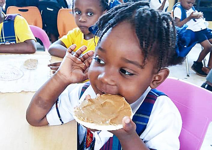a young girl in Haiti eats bread with peanut butter as part of fftp school feeding programs