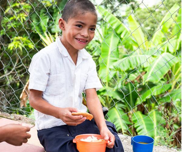 A young boy in Honduras enjoys a meal provided by Food For The Poor