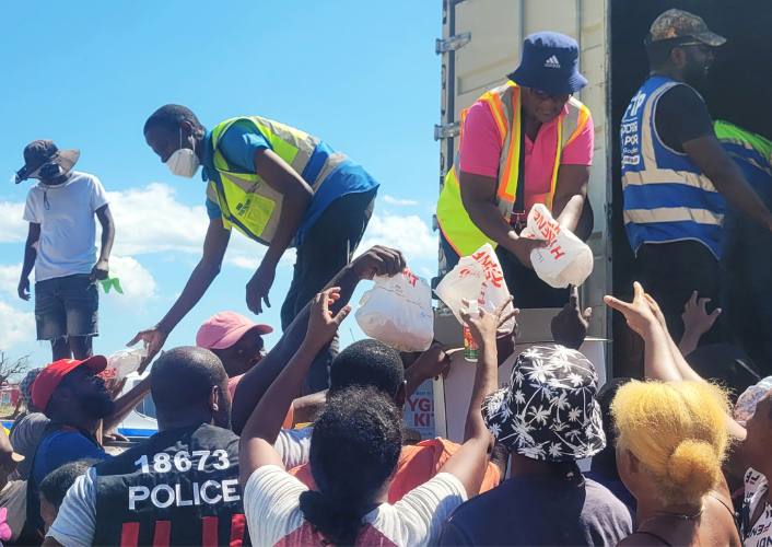 Relief supplies being handed out to a crowd of people as part of food for the poor jamaica relief after hurricane Melissa