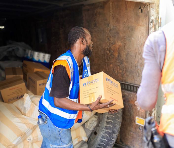 A worker from Food For The Poor Haiti unloads a truck full of boxes of aid