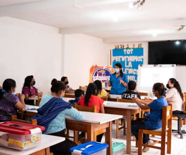 A group of women sit in a classroom listening to a teacher educating them about health in Guatemala where FFTP fights poverty