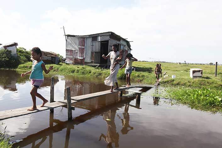 children in guyana playing by a rural shack