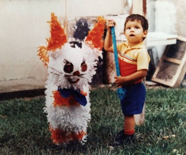 Jesus standing next to a piñata at his 2nd birthday party