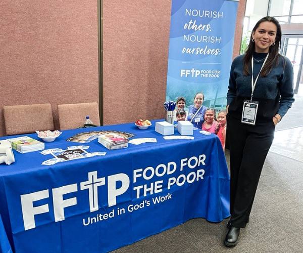 Ana Duarte stands next to a FFTP table at a conference