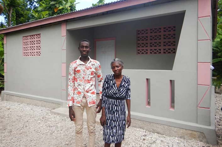 A man and woman stand in front of a new home in Haiti.
