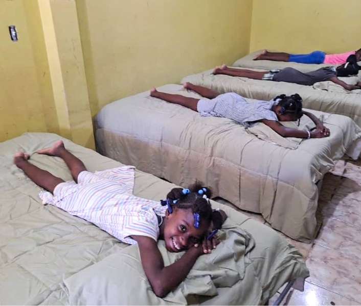 4 girls lay on their new beds at a group home in Haiti