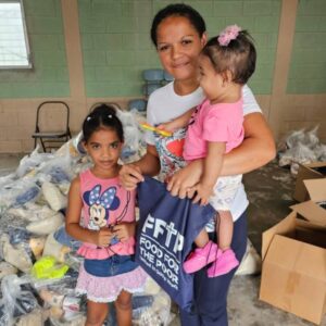 A mother and her two young girls gather supplies provided by FFTP for hurricane preparedness