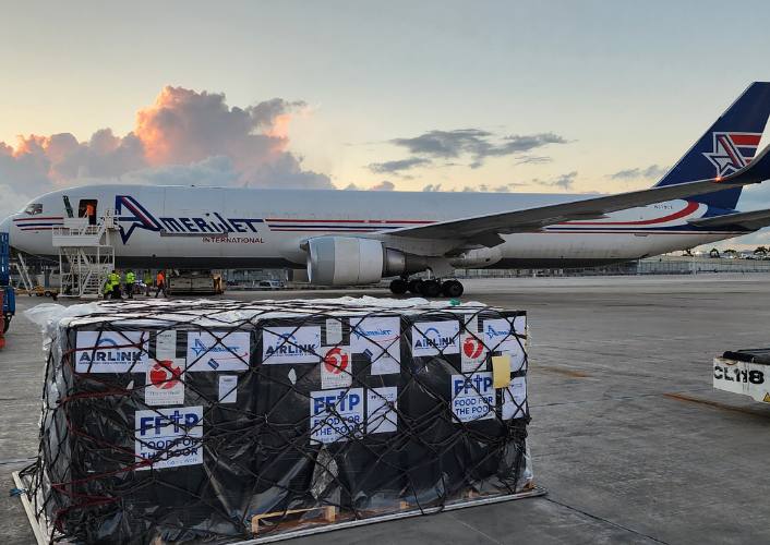 Amerijet plane on the runway of MIA airport and pallets of hygiene kits waiting to be flown to Haiti