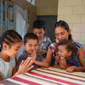 A family in Honduras pray around the table in their home provided by Indiana Church and FFTP