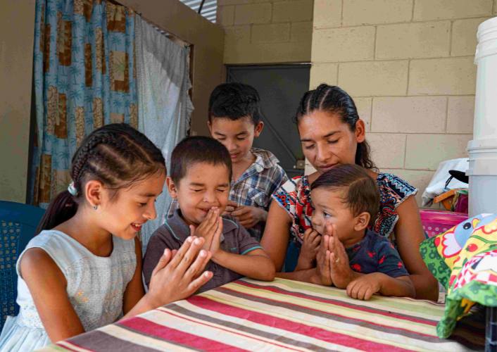 A family in Honduras pray around the table in their home provided by Indiana Church and FFTP