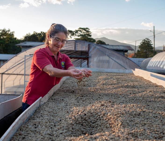 Lorena holds coffee beans from her farm celebrating the achievements she has made as a women