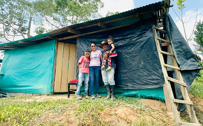 A family stands together in front of their house.