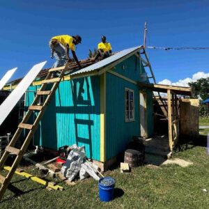 Two men repairing a roof damaged by Hurricane Melissa part of long-term recovery in Jamaica