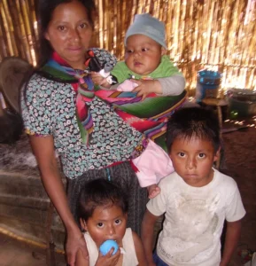 Maria stands with her three children in her home in Guatemala.