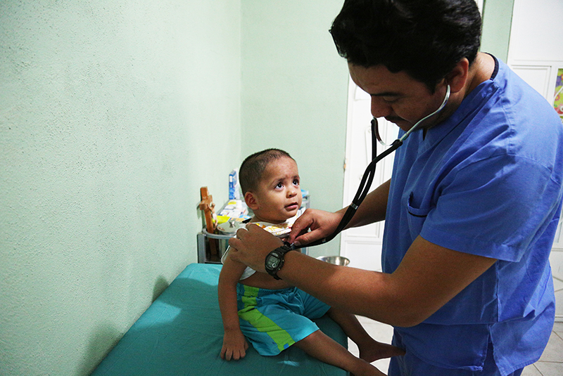 A doctor in Guatemala listens to a toddler's chest using a stethoscope.