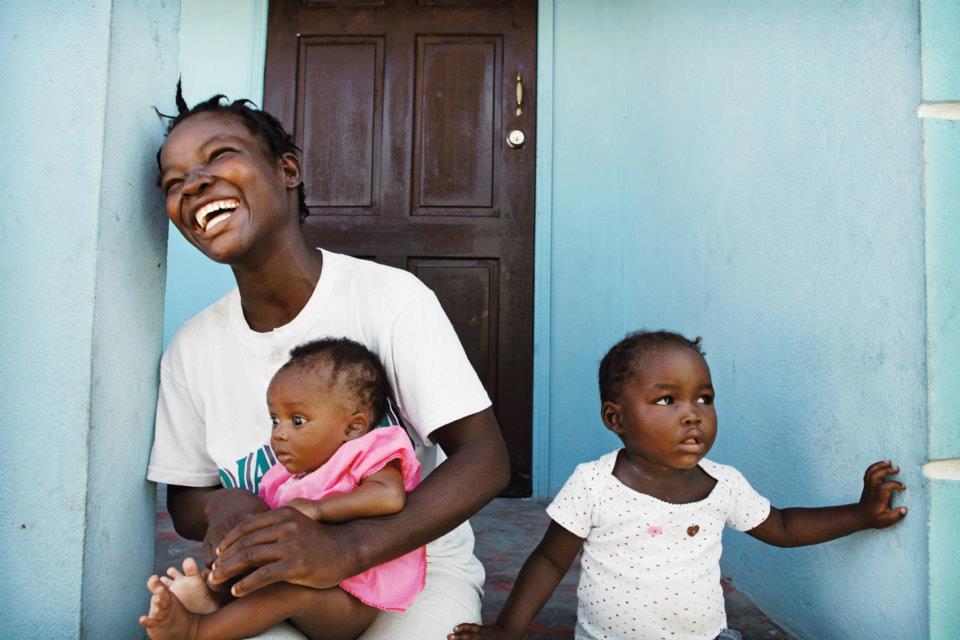 A mother rejoices after settling into her home in May 2012, which was made possible by Food For The Poor donors.