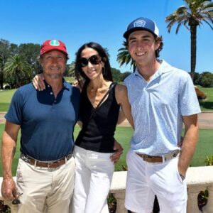 Rafe Cochran poses for a photo with his parents on a golf course